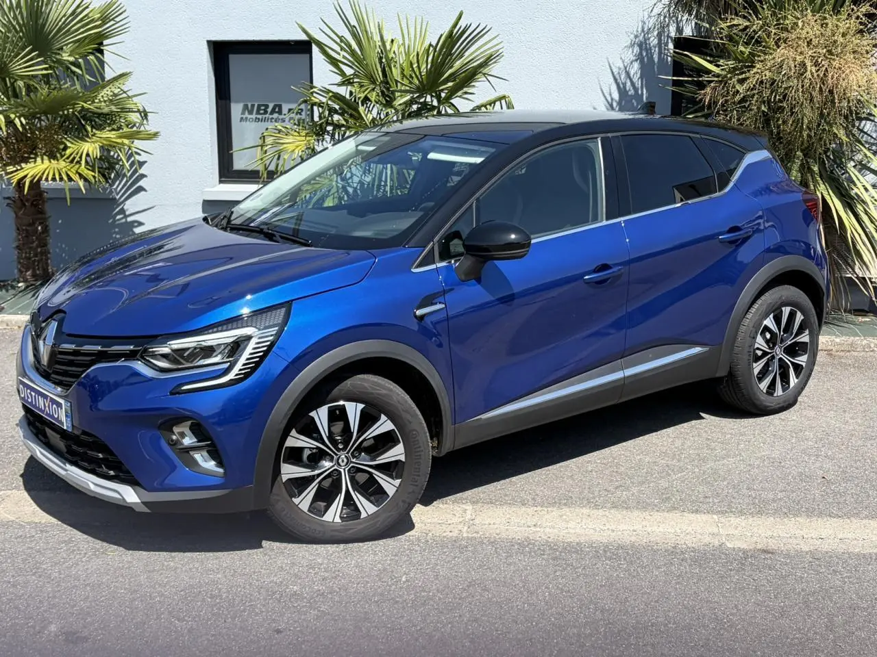 Renault Captur TCE 90 Techno 2024 en bleu Iron avec toit noir, vue 3/4 avant côté droit.