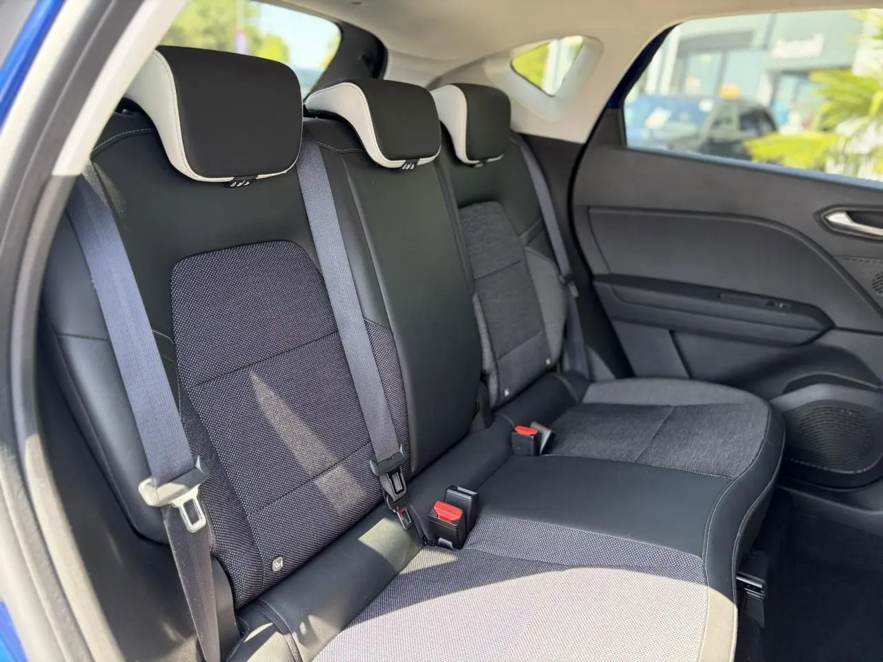 Vue intérieure des sièges arrière noirs et gris du Renault Captur TCE 90 Techno 2024, avec appuis-tête et ceintures visibles.