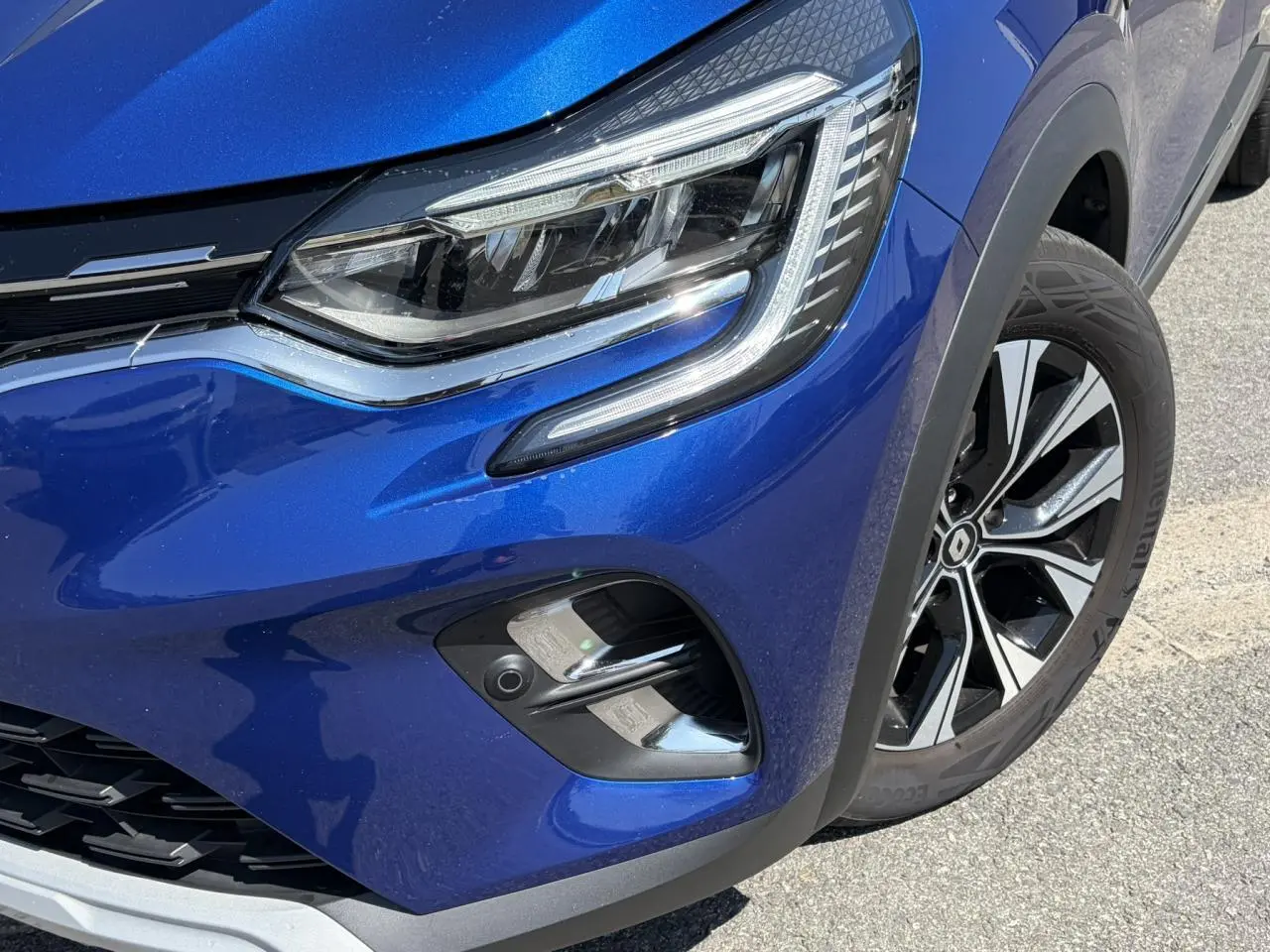 Gros plan sur l'avant droit du Renault Captur bleu Iron avec optique LED et jante alliage 17 pouces.