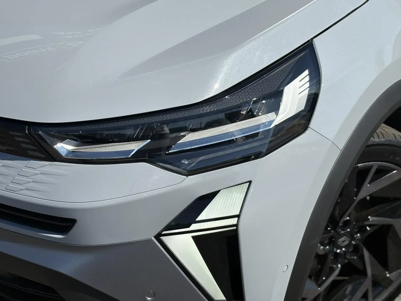 Gros plan sur le phare avant droit gris Rafale du Renault SYMBIOZ 2025 avec jante noire et détails LED distinctifs.