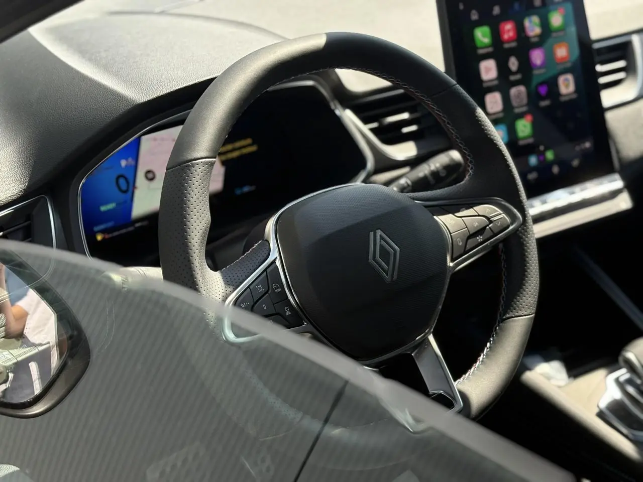 Vue rapprochée du volant noir avec logo Renault sur le tableau de bord numérique et écran tactile du Renault Symbioz.