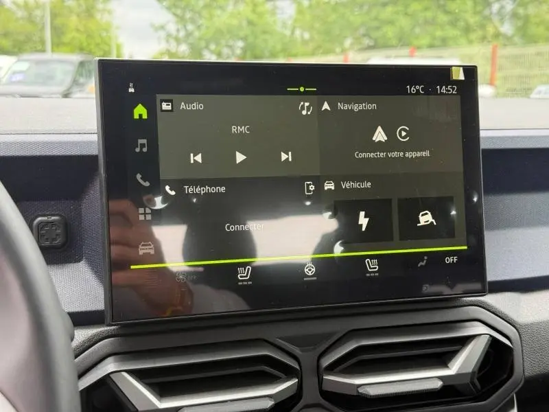 Écran tactile central du tableau de bord du Dacia Duster gris Schiste, affichant les menus audio et navigation.