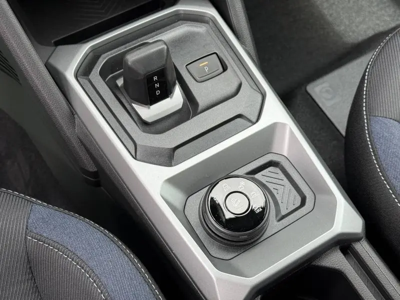 Vue rapprochée de la console centrale grise du Dacia Duster 2026 avec levier de boîte auto et sélecteur de modes de conduite.