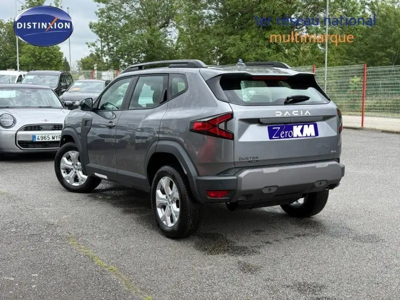 Vue 3/4 arrière droite du Dacia Duster 1.2 hybrid-G 150ch gris Schiste avec barres de toit et jantes alu.