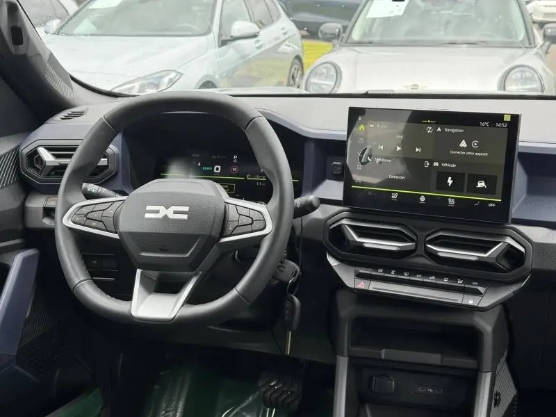 Vue intérieure frontale du tableau de bord du Dacia Duster gris, avec volant multifonction et écran tactile central.