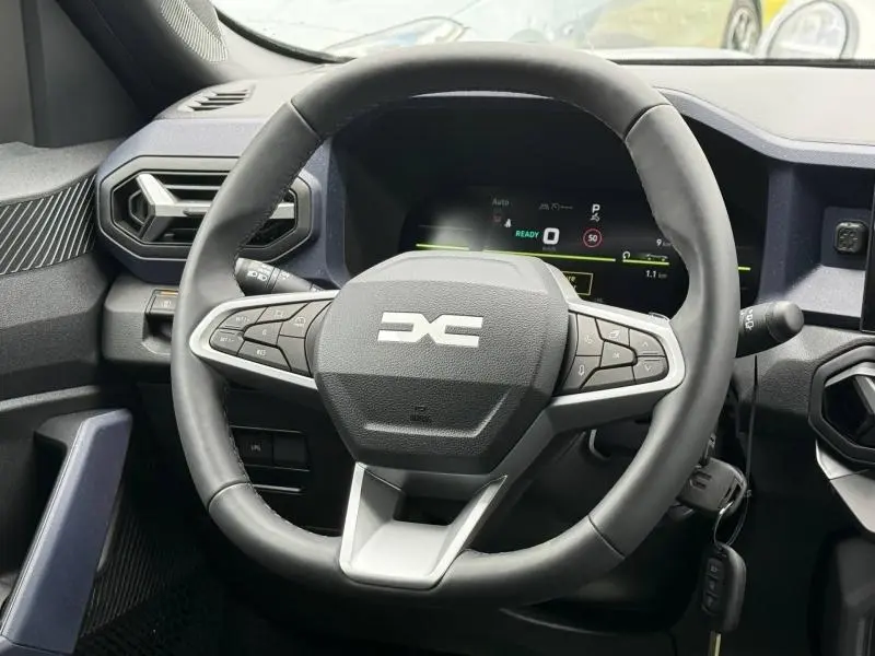 Vue frontale du volant multifonction noir et gris du Dacia Duster 2026, avec tableau de bord numérique en arrière-plan.