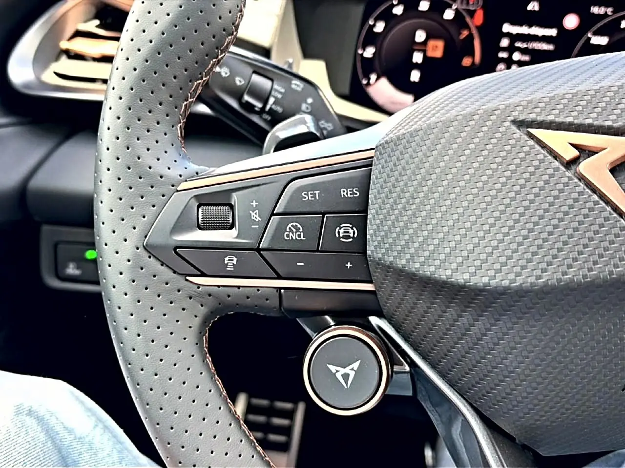 Gros plan sur le volant cuir perforé de la CUPRA Terramar 2026 avec commandes multifonctions et logo cuivre.