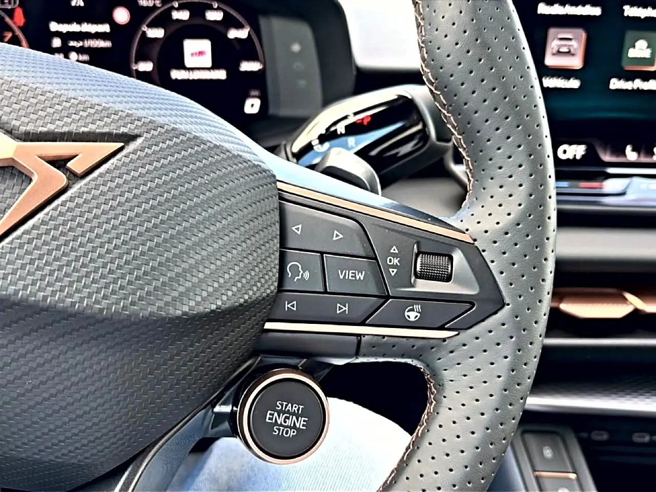 Gros plan sur le volant cuir perforé noir avec commandes multifonctions et bouton start/stop du CUPRA Terramar 2026.