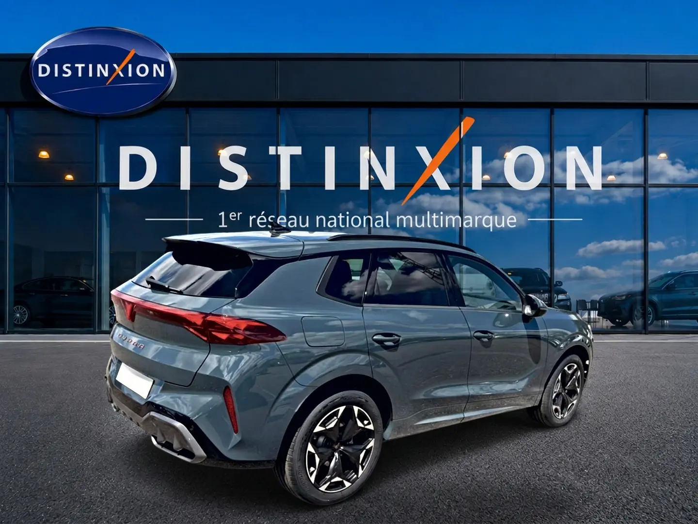 Vue 3/4 arrière droite d'un CUPRA Terramar bleu fjord avec jantes 19 pouces devant une vitrine Distinxion.