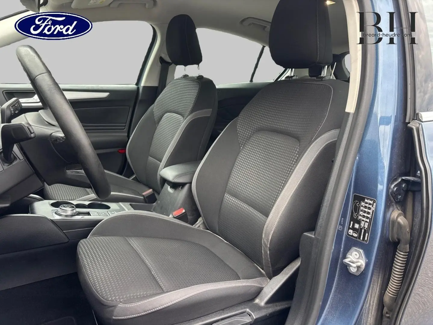 Vue intérieure côté conducteur d'une Ford Focus 2020 bleu azur métallisé, sièges tissu noir avec surpiqûres grises.