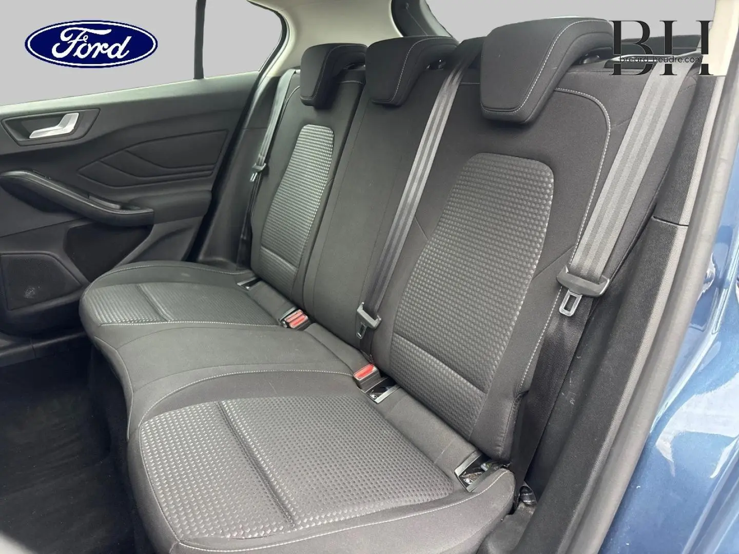 Vue latérale de la banquette arrière noire en tissu de la Ford Focus 1.5 EcoBlue bleu azur métallisé, avec ceinture de sécurité visible.