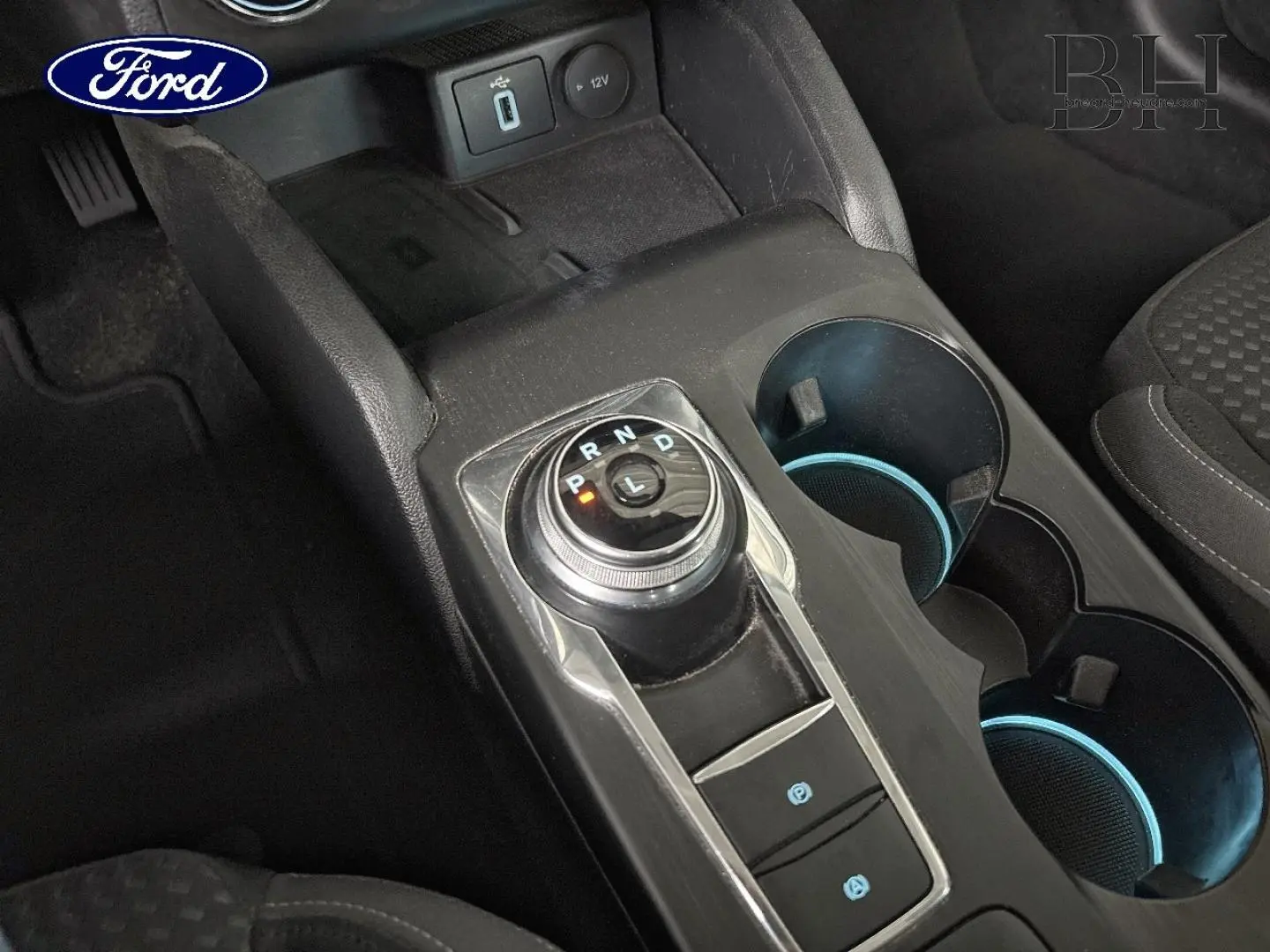 Gros plan sur la console centrale de la Ford Focus 1.5 EcoBlue 2020, avec sélecteur rotatif de boîte auto et porte-gobelets.
