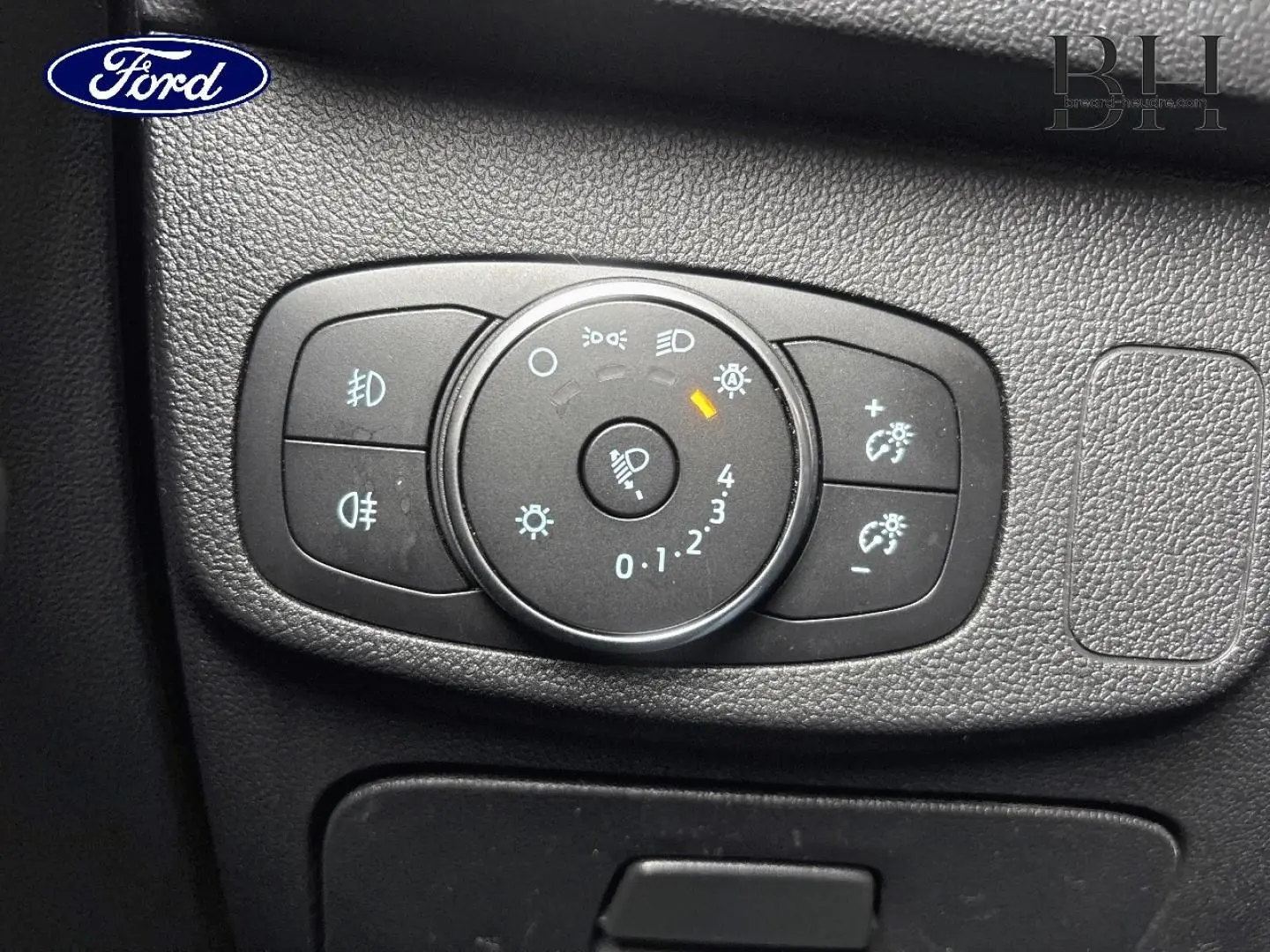 Gros plan sur la commande des phares du Ford Focus 1.5 EcoBlue 2020, tableau de bord noir texturé.