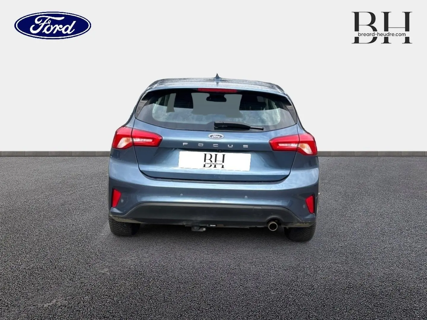 Vue arrière d'une Ford Focus bleu azur métallisé de 2020, avec feux rouges et sortie d'échappement chromée visible.
