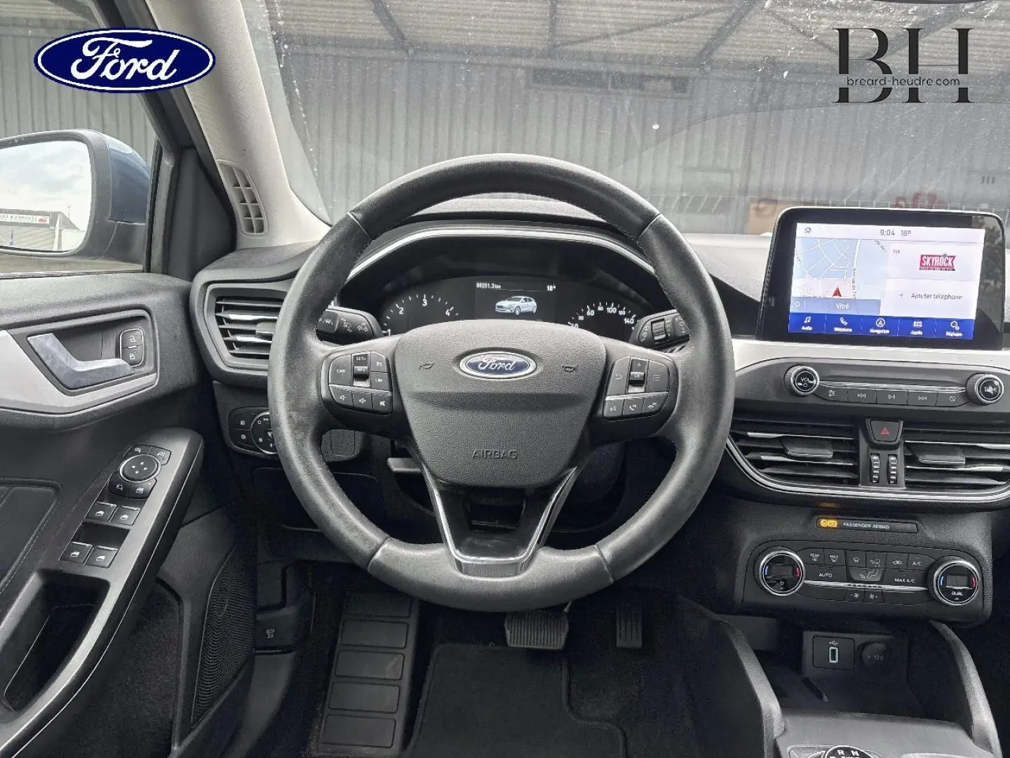 Vue intérieure centrée sur le volant cuir multifonction et l’écran tactile du tableau de bord de la Ford Focus 2020.