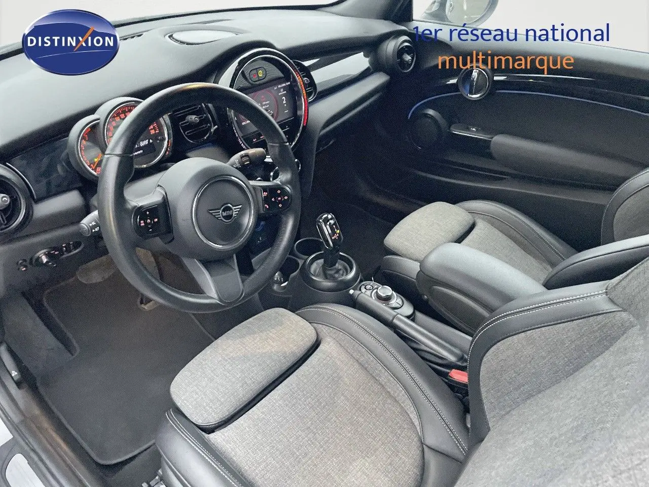 Intérieur de la MINI Cabriolet F57 2023, vue côté conducteur, sièges tissu gris et cuir noir, tableau de bord moderne.