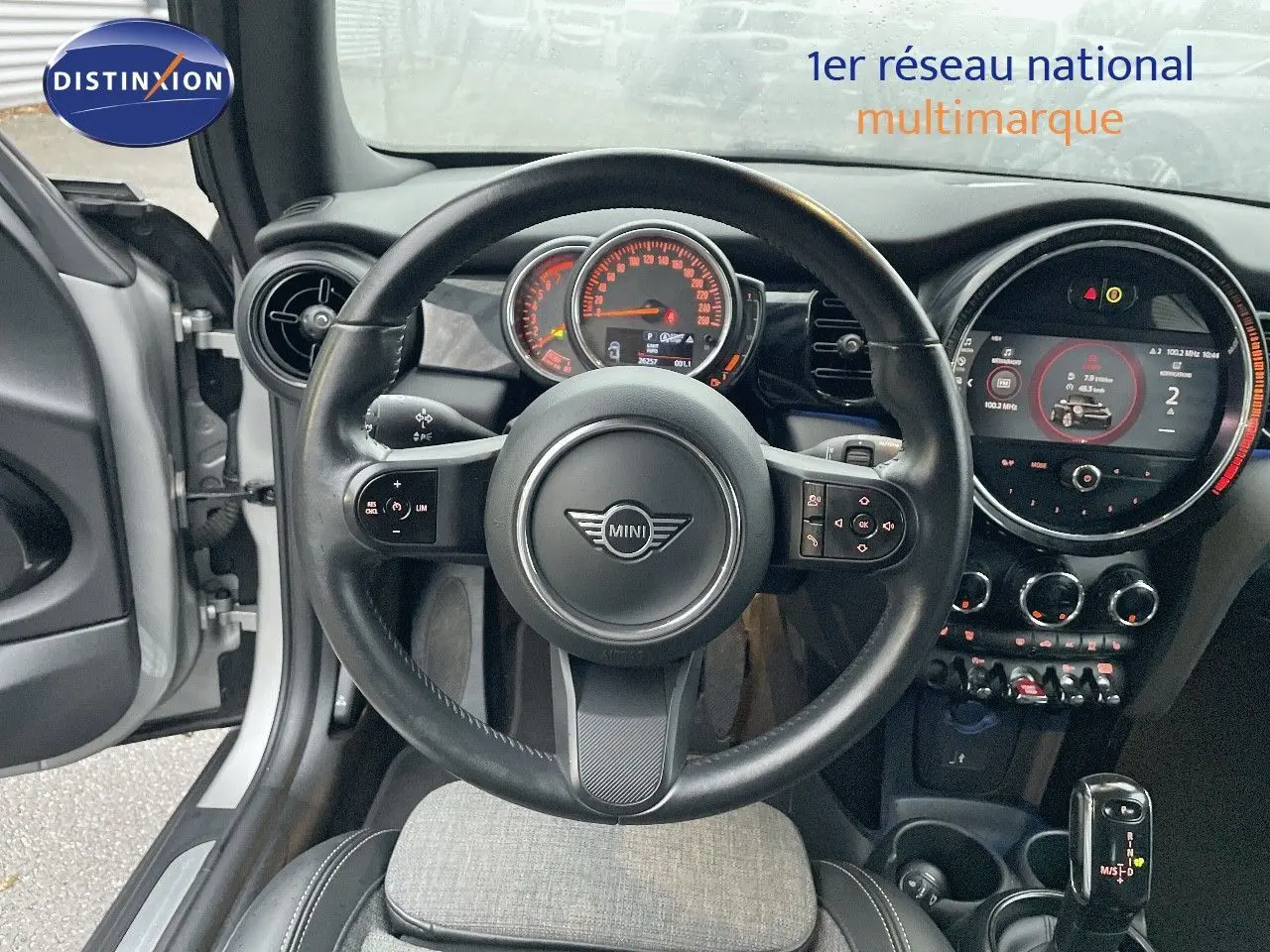 Vue intérieure centrée sur le volant et le tableau de bord d'une MINI Cabriolet Melting Silver 2023, détails modernes visibles.