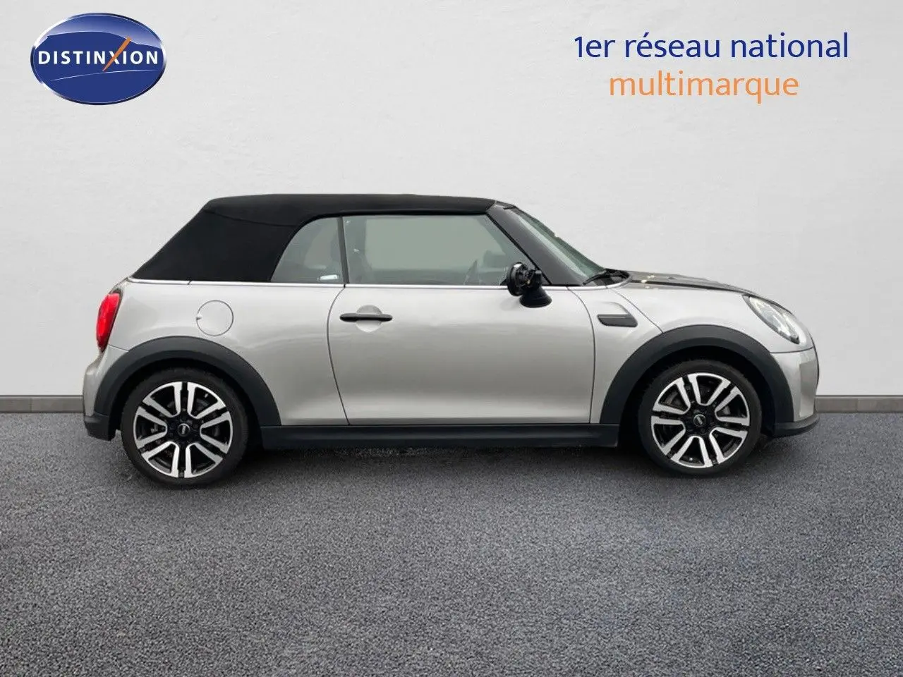 Profil droit d'une MINI Cabriolet 2023 couleur argent métallisé avec toit noir fermé sur fond neutre.