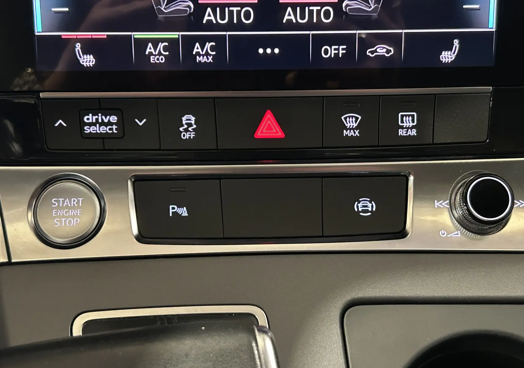 Gros plan sur la console centrale de l'Audi A6 Avant noire 2019, montrant les commandes de climatisation et démarrage moteur.