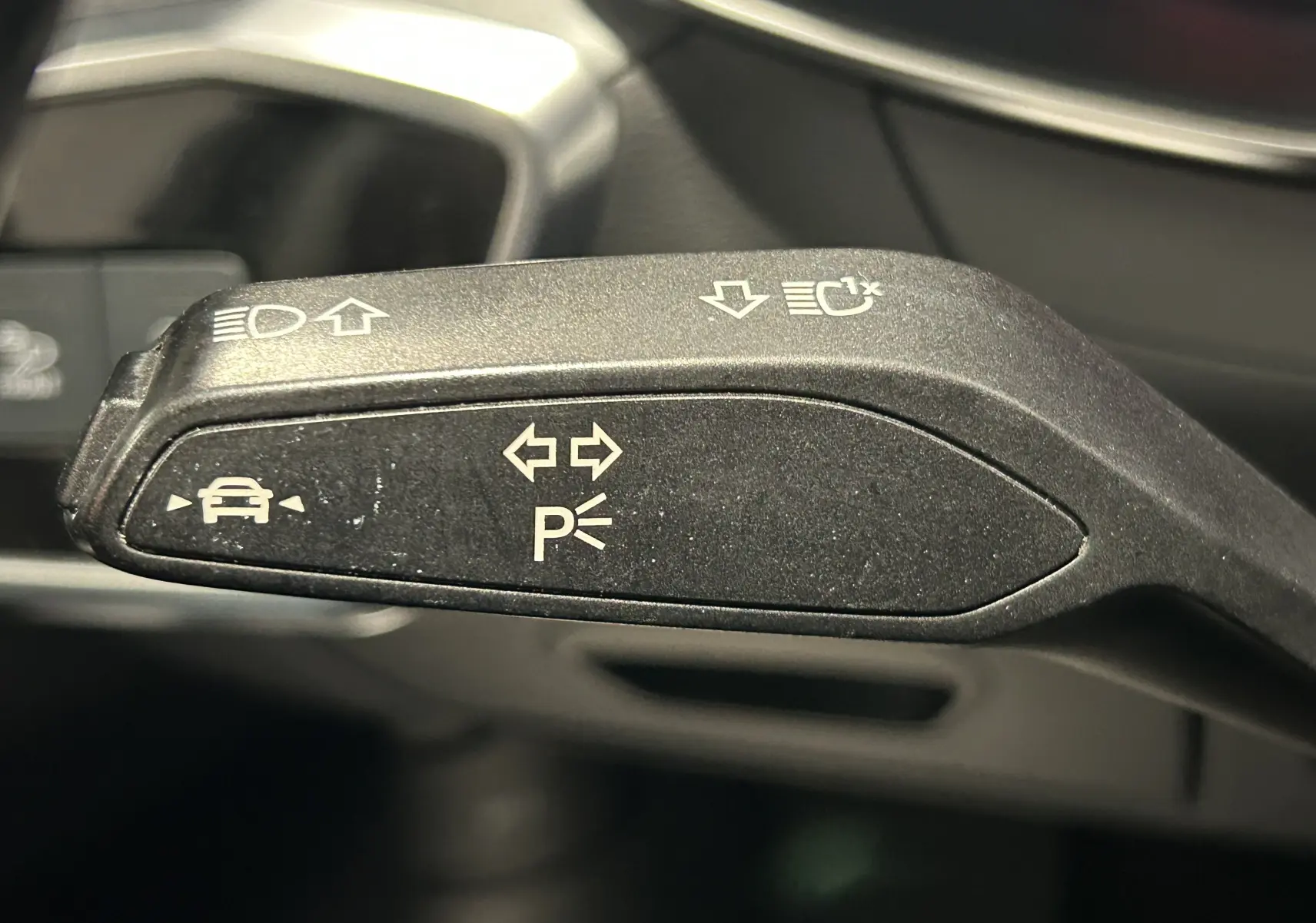 Gros plan sur la commande de clignotant et assistance au stationnement dans l'habitacle d'une Audi A6 Avant noire.