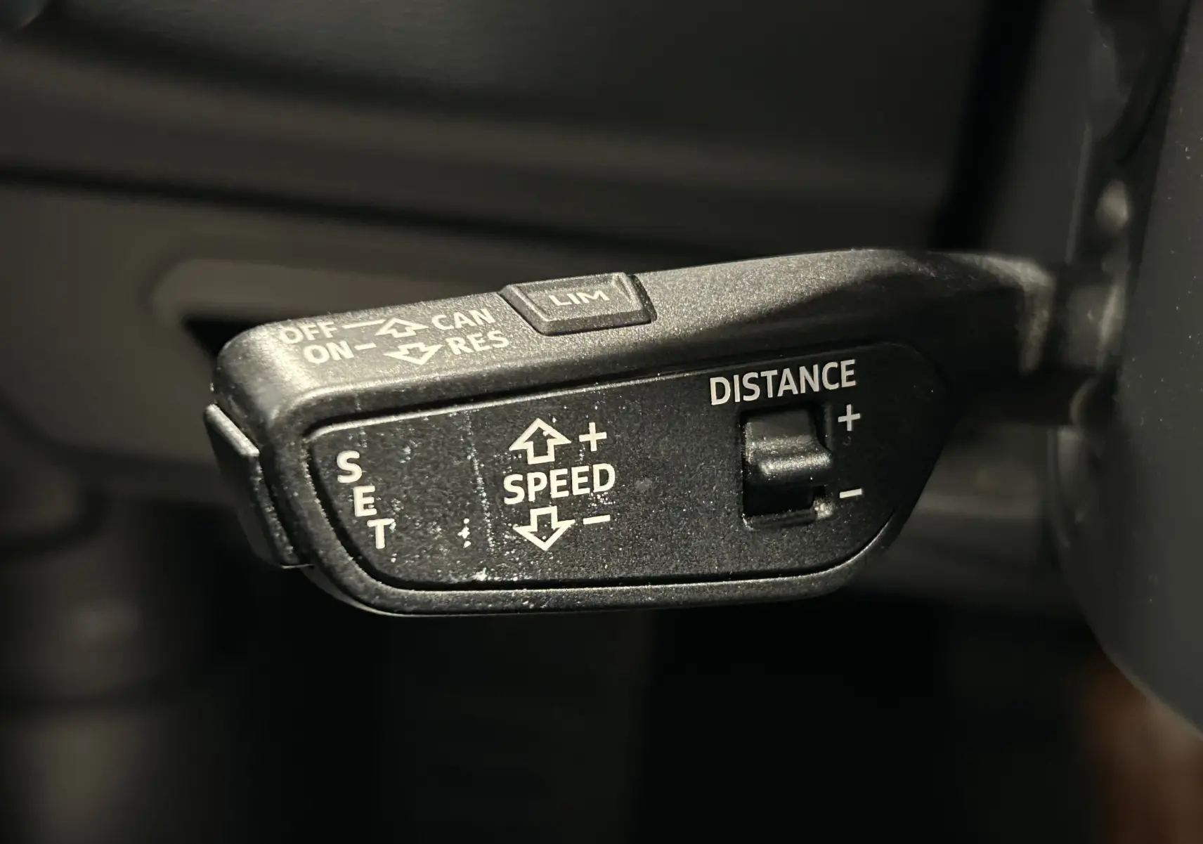 Gros plan sur la commande de régulateur de vitesse de l'Audi A6 Avant 40 TDI noire, avec réglage de la distance et vitesse.