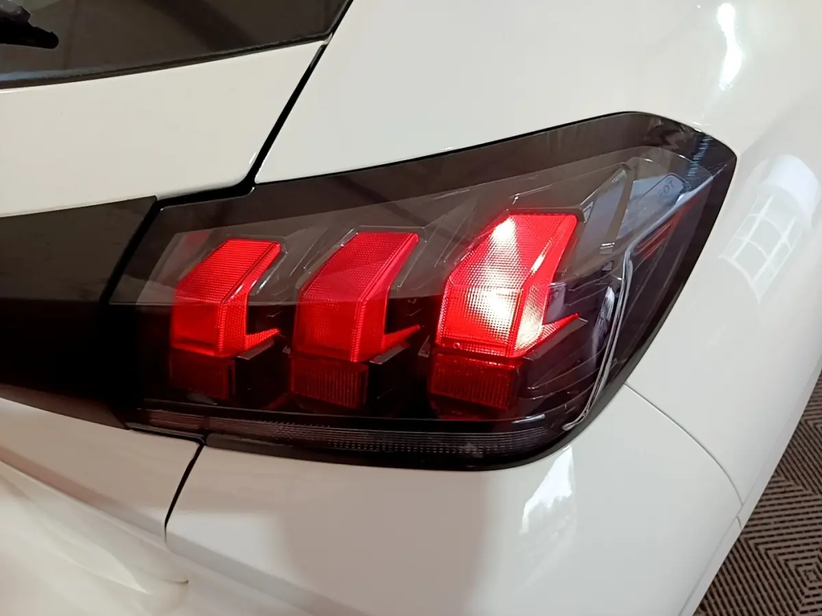 Gros plan sur le feu arrière droit rouge de la Peugeot 208 blanche, version 1.5 BlueHDi 100 S&S Premium 2022.