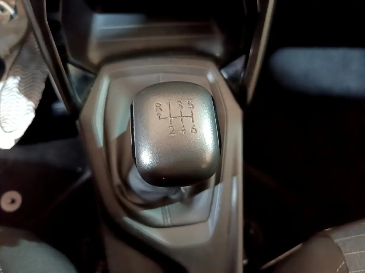 Gros plan sur le levier de vitesses manuel de la Peugeot 208 blanche, montrant les six rapports et la marche arrière.