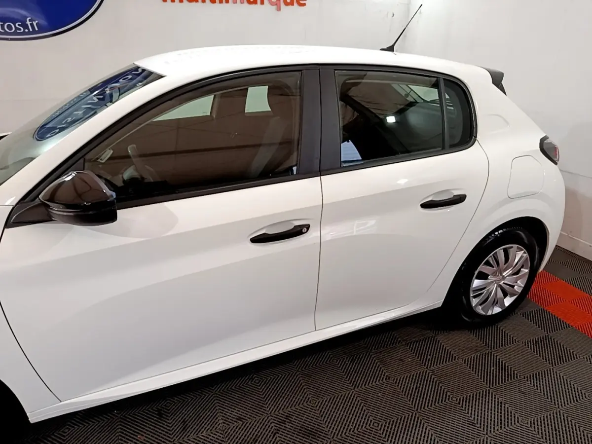 Vue latérale côté gauche d'une Peugeot 208 blanche, mettant en valeur les poignées de porte et les jantes en alliage.