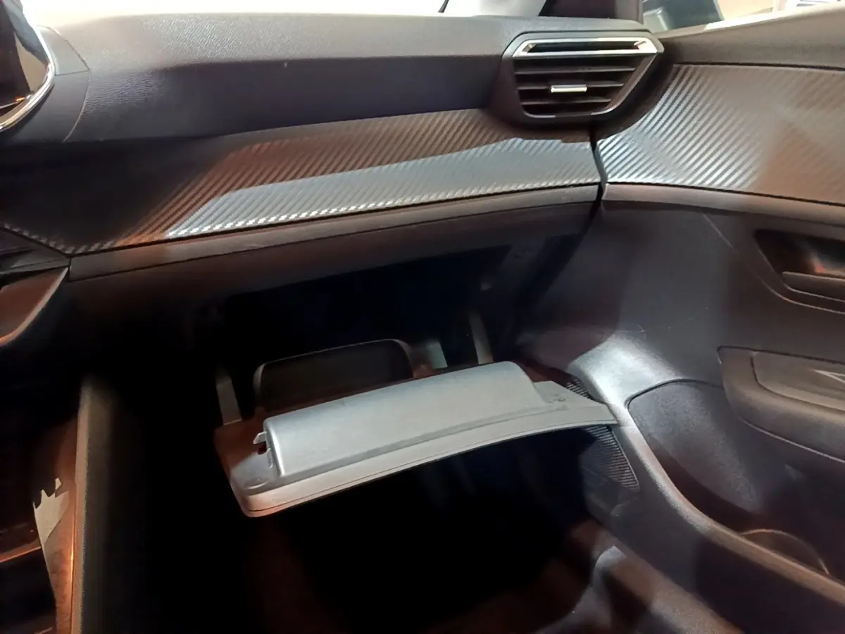 Intérieur de la Peugeot 208 1.5 BlueHDi 2022, vue du coffre à gants ouvert côté passager, tableau de bord noir.