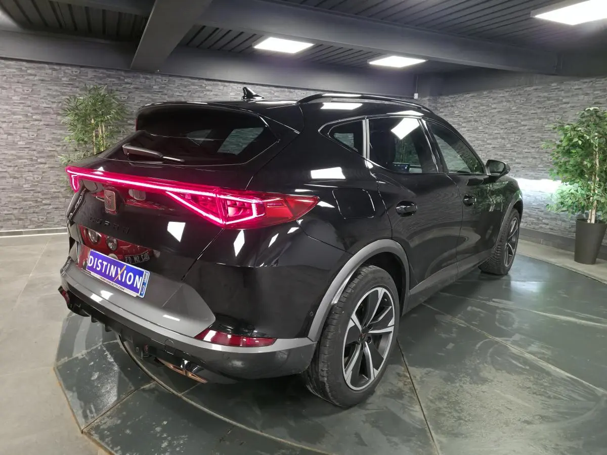 Vue 3/4 arrière droite du CUPRA Formentor noir avec bandeau LED arrière et jantes alliage 18 pouces en intérieur showroom.