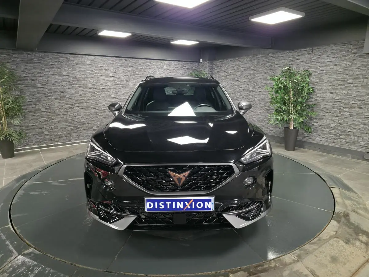 Vue avant d'une CUPRA Formentor noire avec calandre marquée et logo cuivre dans un showroom.