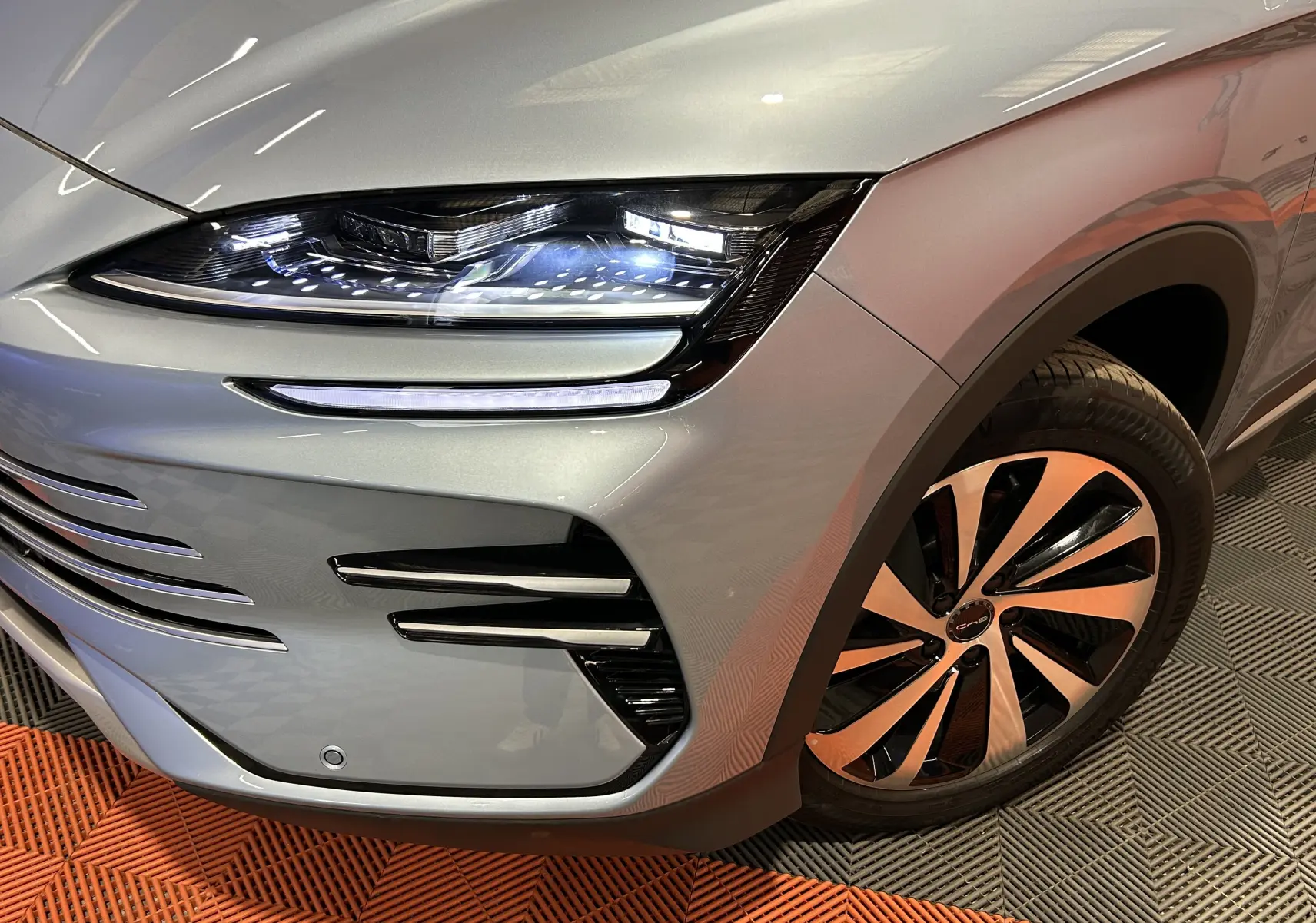 Gros plan sur l'avant droit du BYD SEAL U gris Tian Qing Metal avec phares LED allumés et jante bicolore.