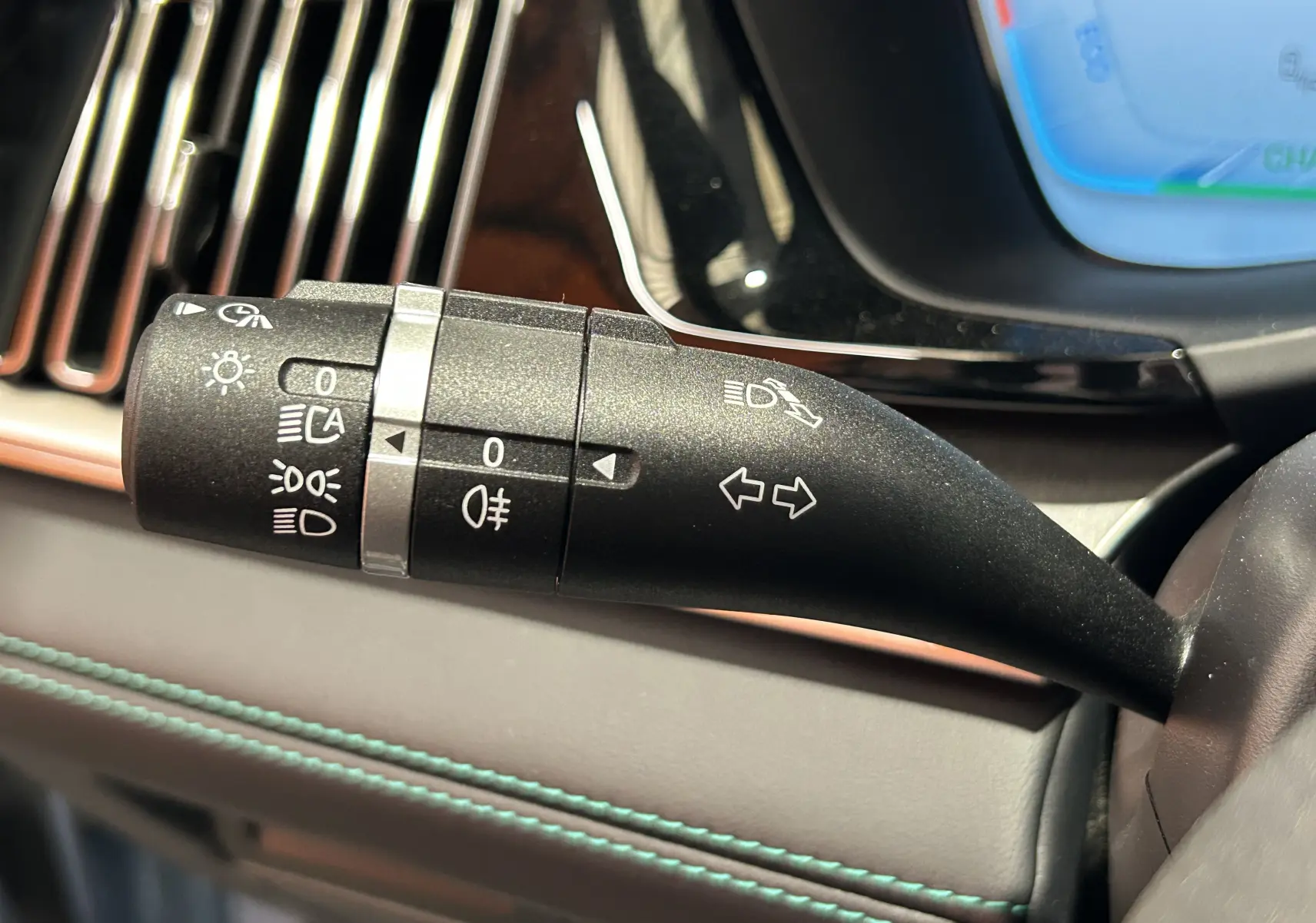 Gros plan sur la commande de clignotants et feux du BYD SEAL U, intérieur cuir noir avec surpiqûres bleues.