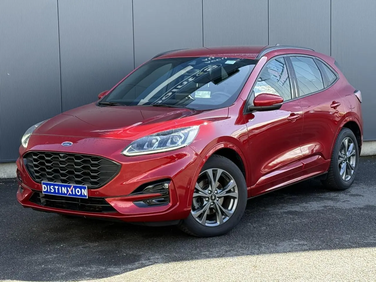Ford Kuga 2024 rouge Lucifer en 3/4 avant droit, avec calandre noire et jantes alliage 18 pouces.