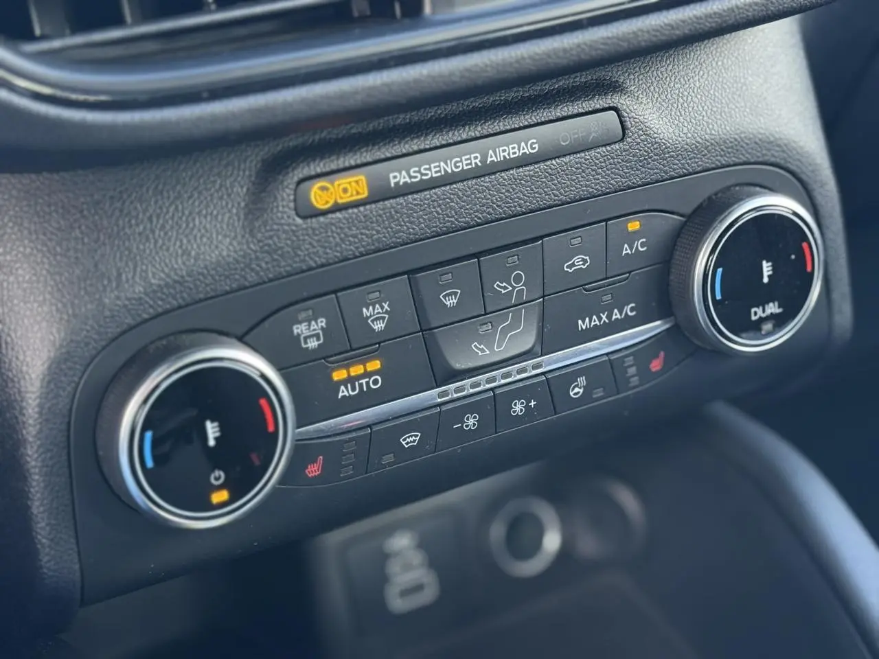 Gros plan sur la console de climatisation automatique bi-zone avec commandes chauffantes du Ford Kuga 2024 rouge Lucifer.