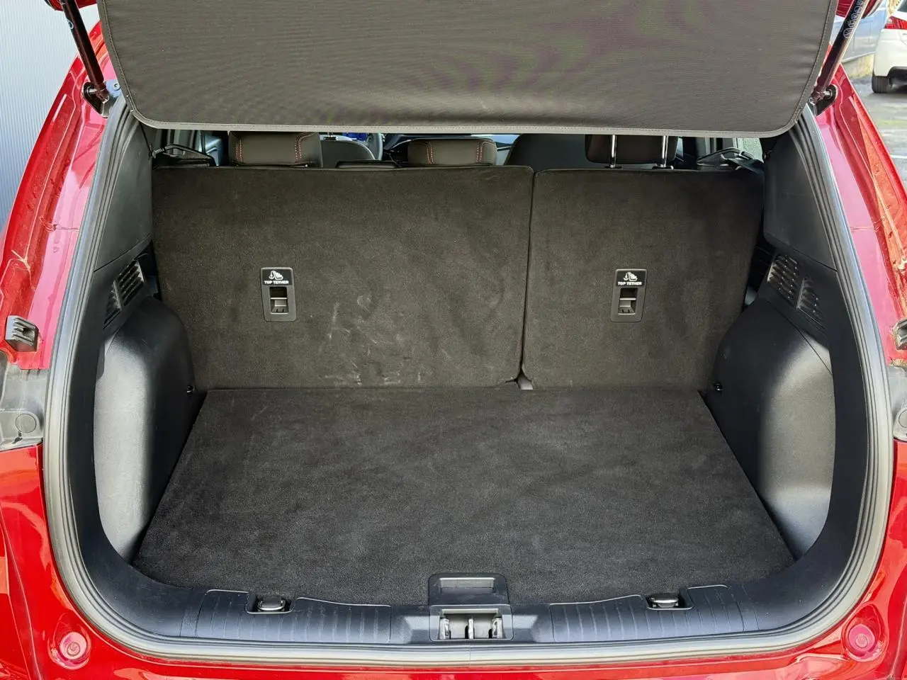 Coffre ouvert du Ford Kuga 2.0 EcoBlue rouge Lucifer, montrant l’espace de chargement arrière vide et les dossiers de sièges rabattus.