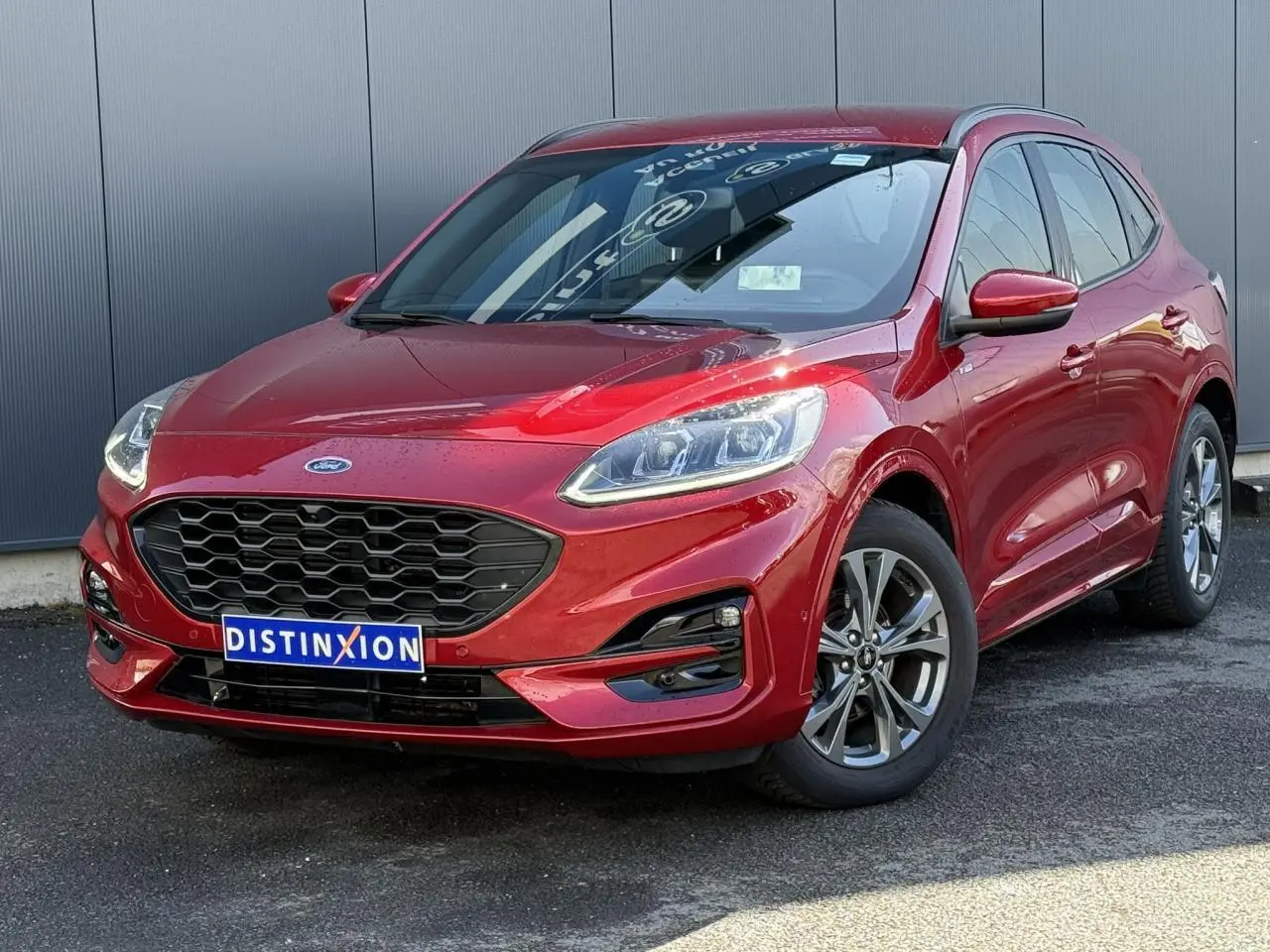 Ford Kuga 2024 rouge Lucifer en 3/4 avant droit, avec calandre noire et jantes alliage 18 pouces.