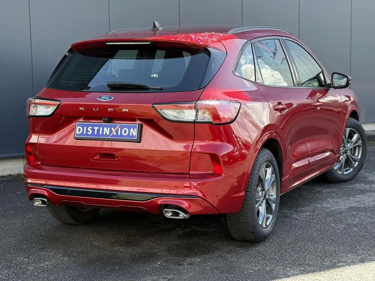 Vue 3/4 arrière droite du Ford Kuga rouge Lucifer 2024 avec double sortie d’échappement et jantes alliage 18 pouces.