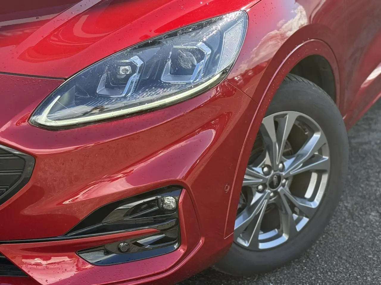Gros plan sur l'avant droit rouge Lucifer du Ford Kuga 2024, mettant en valeur le phare LED et la jante alliage 18 pouces.
