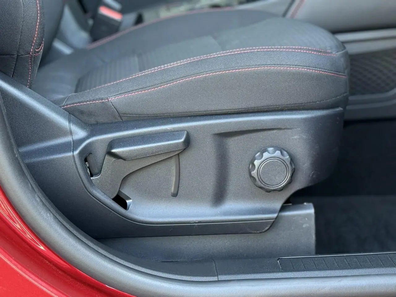 Gros plan sur le côté gauche du siège avant noir avec surpiqûres rouges du Ford Kuga Rouge Lucifer 2024.