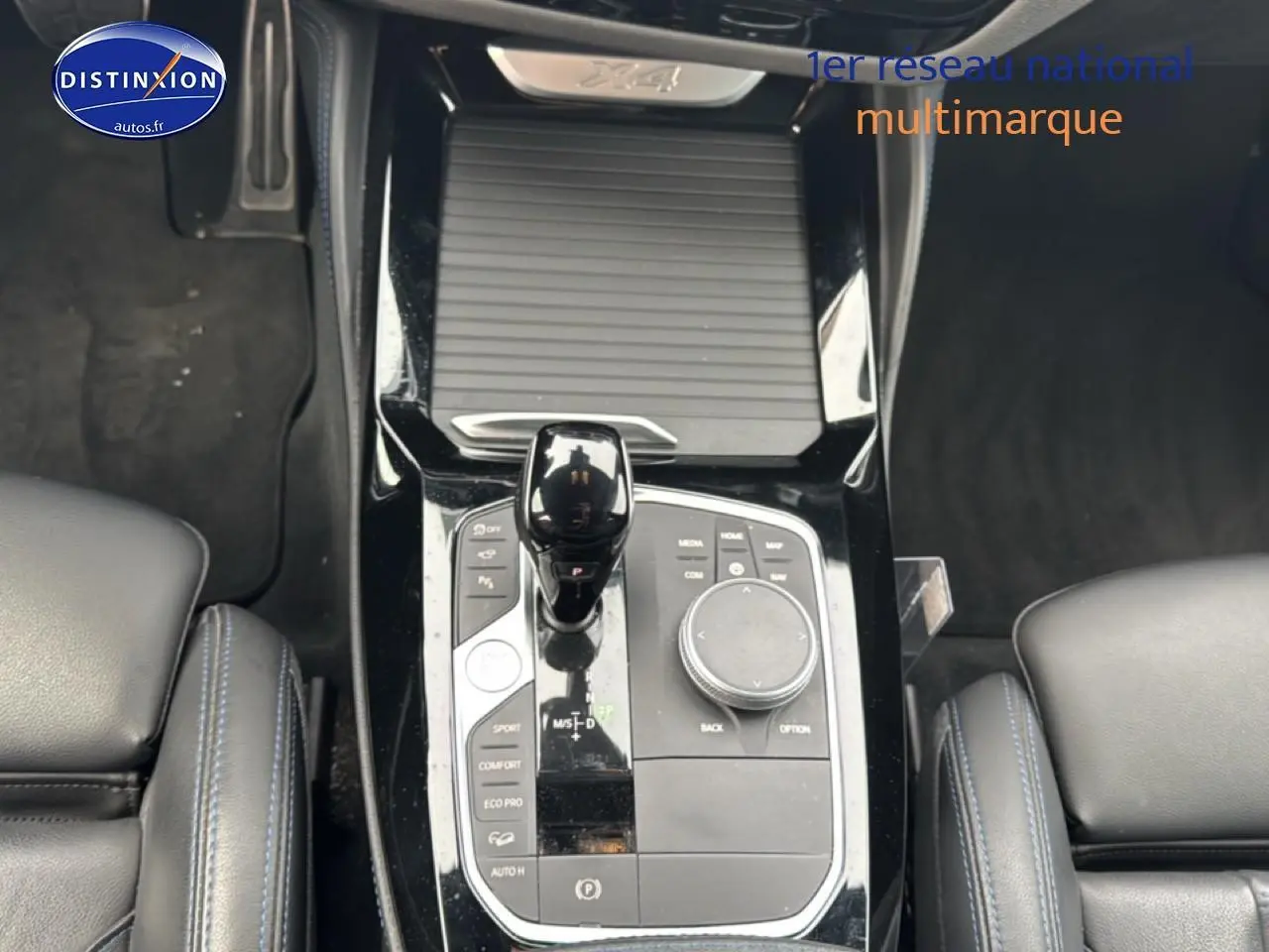 Vue plongeante sur la console centrale noire du BMW X4 xDrive30d 2022 avec levier de vitesse et commandes multifonctions.