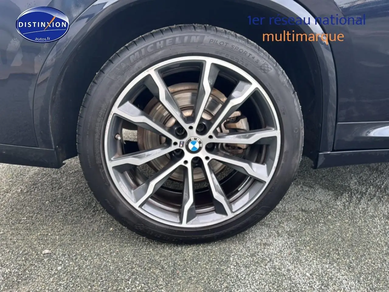 Gros plan sur la jante alu grise et le pneu Michelin du côté arrière droit d’un BMW X4 noir.