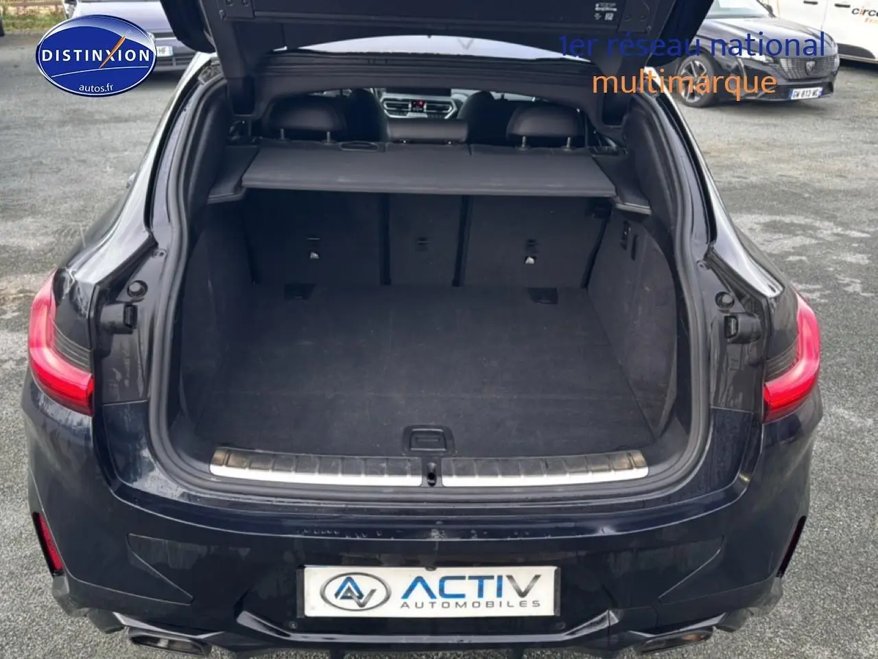 Vue arrière ouverte du coffre d'un BMW X4 noir (g02) xdrive30d 286 m sport avec feux arrière LED allumés.