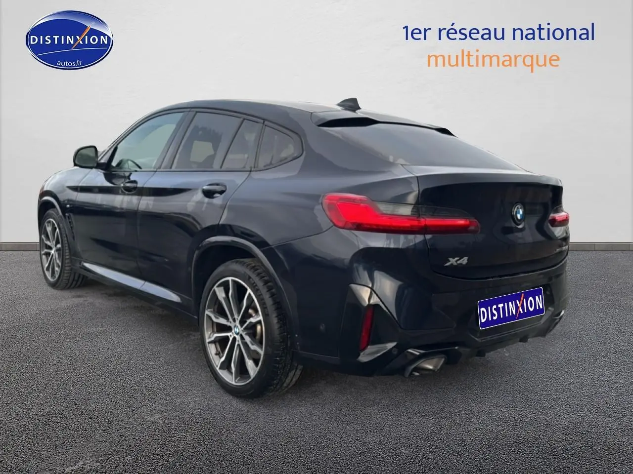 BMW X4 noir vue 3/4 arrière droit, avec feux arrière LED et double sortie d’échappement chromée.