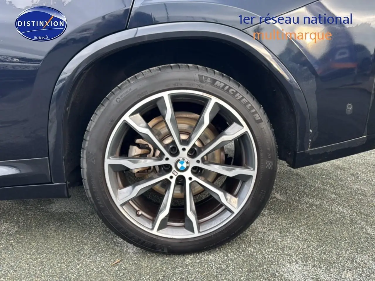 Gros plan sur la roue arrière droite d’un BMW X4 noir avec jante alu à dix branches.