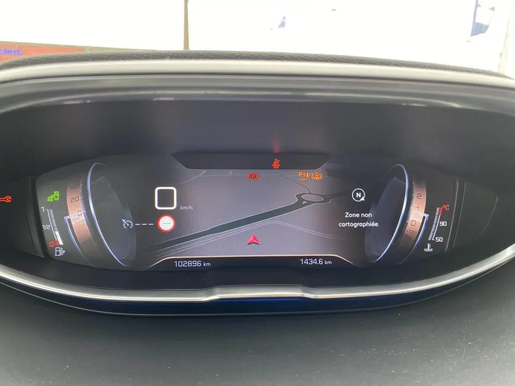 Tableau de bord numérique du Peugeot 3008 blanc, affichant la vitesse à 0 km/h et une carte de navigation en zone non cartographiée.