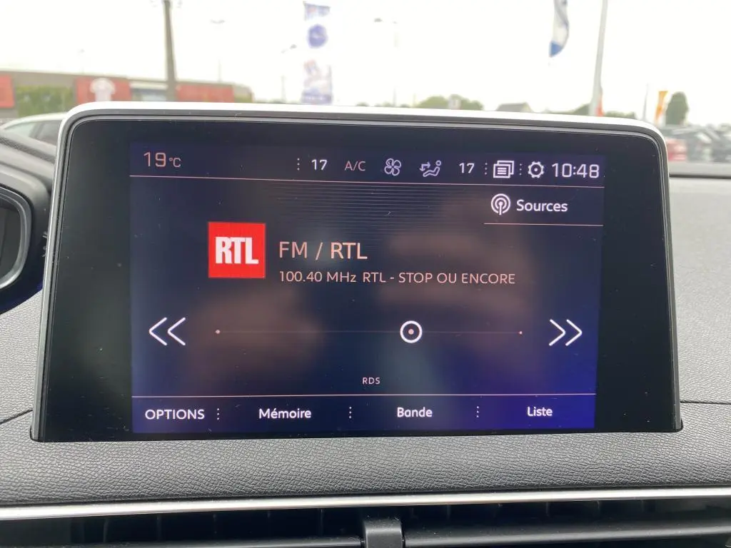Écran tactile central du tableau de bord du Peugeot 3008 blanc, affichant la radio FM RTL à 10h48.