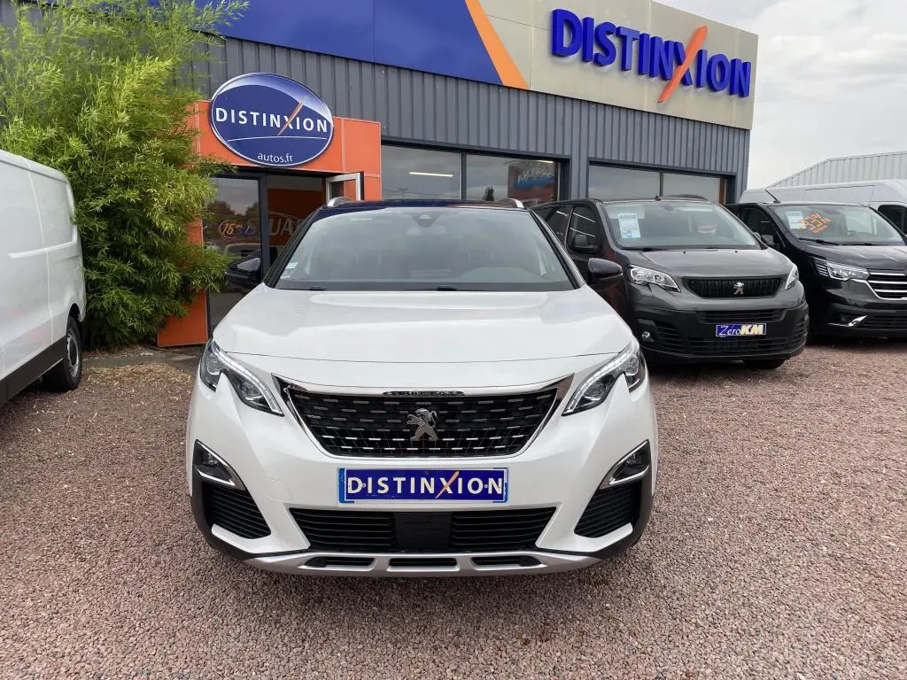 Vue frontale d’un Peugeot 3008 blanc GT Line 2018, avec calandre noire et logo lion distinctif, devant un concessionnaire.