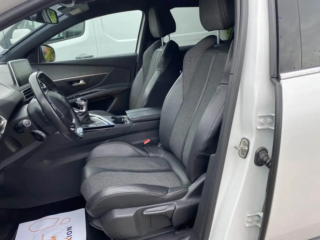 Vue intérieure côté conducteur du Peugeot 3008 blanc 2018, sièges en cuir et tissu, volant et levier de vitesse manuelle visibles.