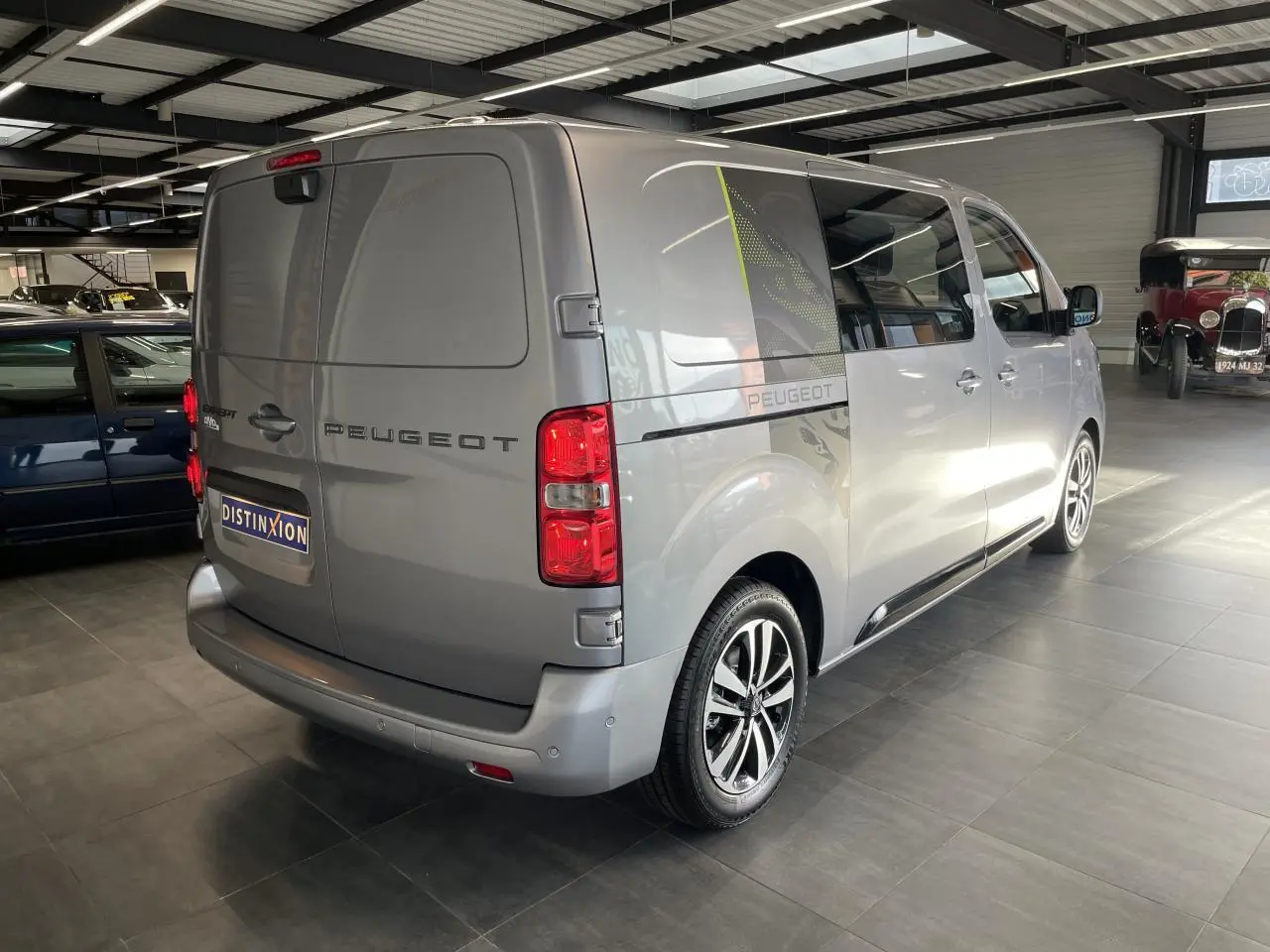 Peugeot Expert Fourgon gris Artense vu 3/4 arrière droit en intérieur avec jantes alliage et décor latéral noir et vert.